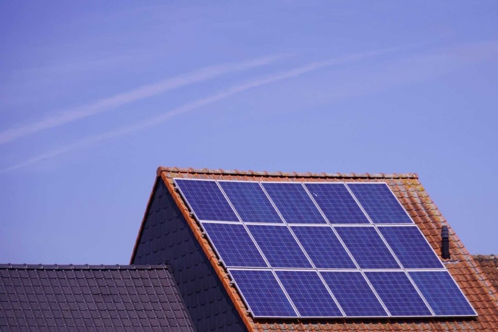 Tiled roof with solar panels, under clear, blue sky - FAS Exteriors