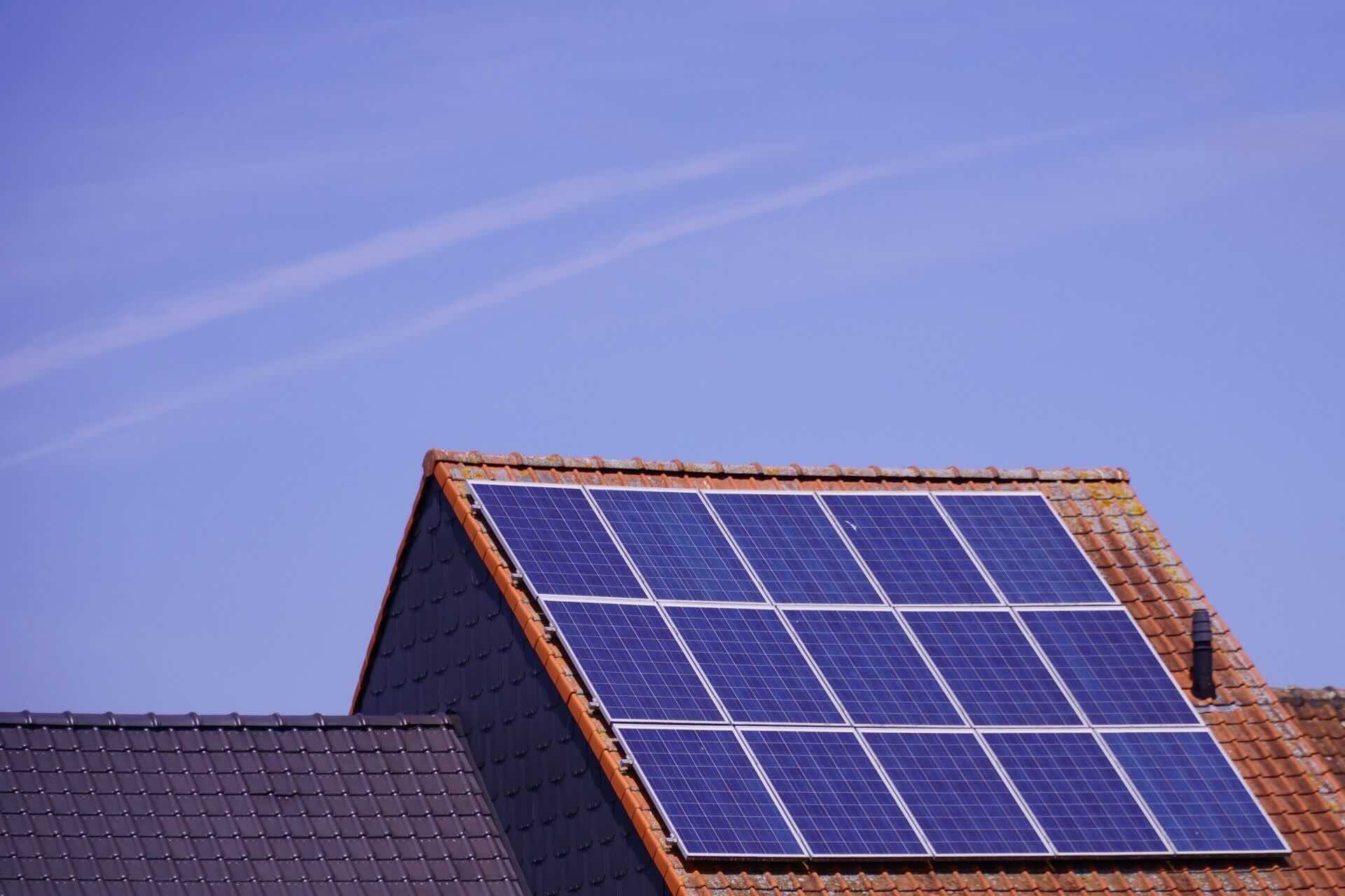 Tiled roof with solar panels, under clear, blue sky - FAS Exteriors